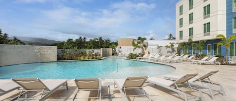 A swimming pool with lounge chairs and a building in the background.