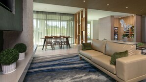 Una sala de estar moderna con un sofá, una mesa de comedor con sillas y una zona de cocina con un refrigerador y una planta en maceta.