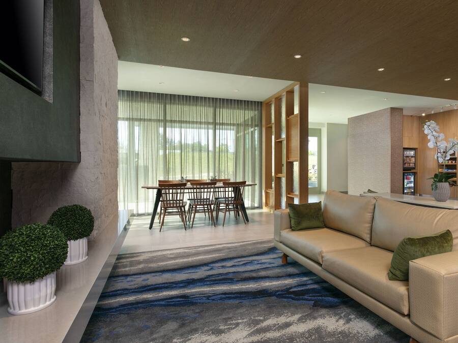 Un salon moderne comprenant un canapé, une table à manger avec des chaises et un coin cuisine avec un réfrigérateur et une plante en pot.
