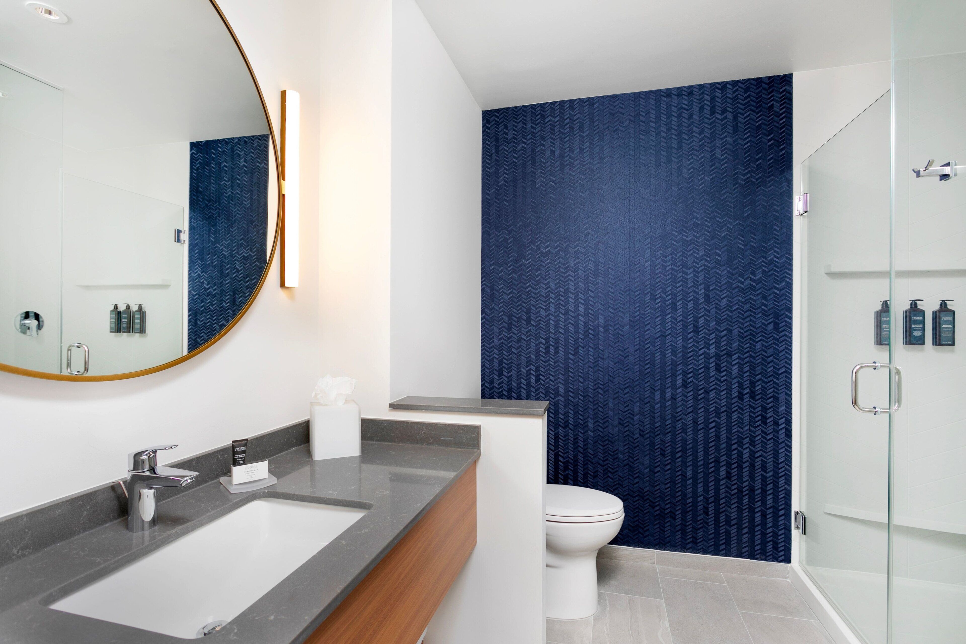 A modern bathroom with a large mirror, a sink, and a toilet.