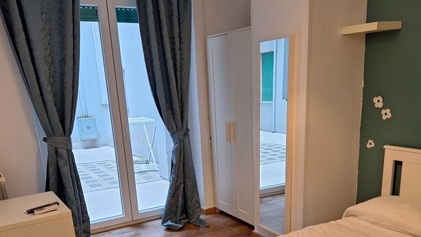 Une chambre à coucher comprenant un lit, une table de chevet, une lampe et une vue sur l’extérieur grâce à une porte vitrée.