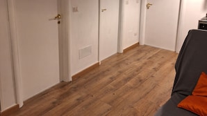 Une chambre d’hôtel avec un plancher en bois, un lit avec un oreiller orange et des portes signalées par un panneau indiquant les toilettes.