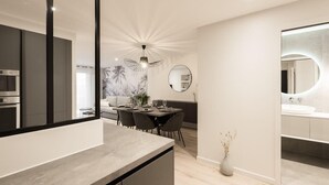 A modern kitchen with a large island, a dining area with a round table, and a bathroom with a large mirror.