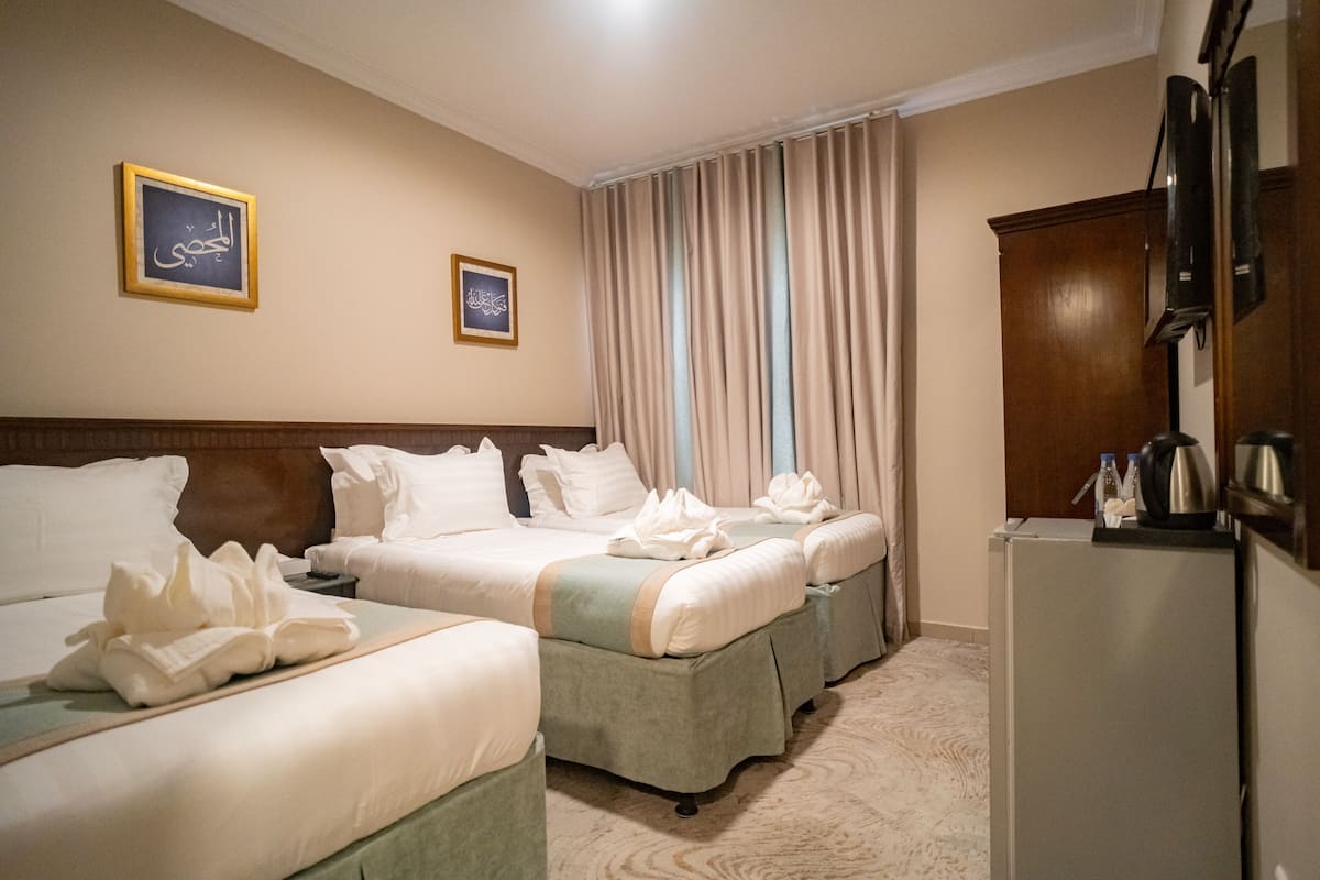 Ein Hotelzimmer mit zwei Betten, einer Minibar und einem großen Fenster mit Vorhängen.