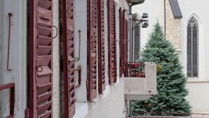 Un edificio con contraventanas rojas, un balcón y un árbol de Navidad.