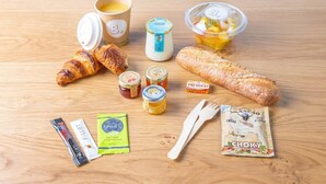 A breakfast spread with croissants, a baguette, yogurt, fruit, jam, honey, and a packet of Choky. - CAUCASE, Annecy Rent Lodge (Annecy)