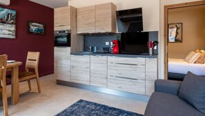 A compact living space with a kitchenette, a dining area, and a bedroom. - CAUCASE, Annecy Rent Lodge (Annecy)