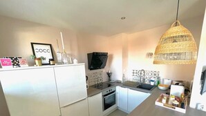 A modern kitchen with white cabinets, a built-in oven, a microwave, and a hanging wicker light fixture. - COSY HOME, Annecy Rent Lodge (Annecy)