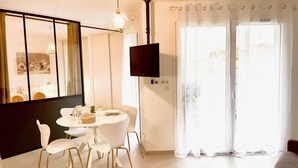 A modern dining area with a round table, white chairs, and a wooden dining table. - Le Quartz Tresum, in a modern residence near the lake, garage included (Annecy)