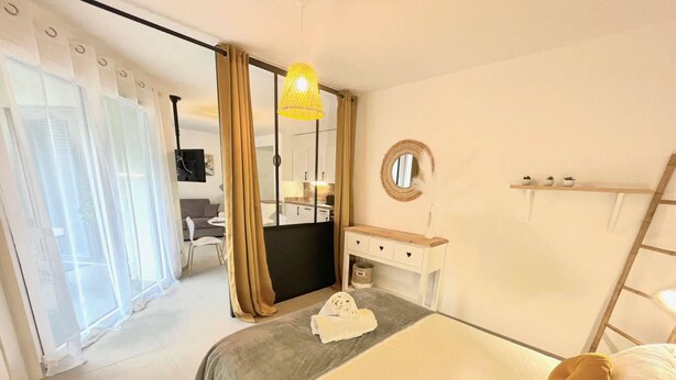 A hotel room with a bed, a bedside table, a mirror, a wardrobe, and a view of the outside. - Le Quartz Tresum, in a modern residence near the lake, garage included (Annecy)