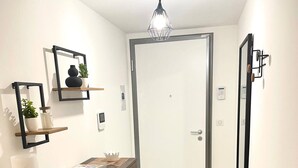A hallway with a wooden dresser, a door, and a mirror on the wall. - Le Quartz Tresum, in a modern residence near the lake, garage included (Annecy)