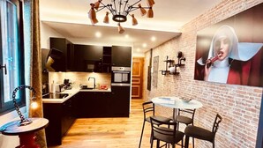 Una cocina moderna con armarios negros, una isla central y un comedor con una mesa redonda y sillas.
