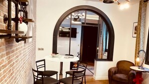 Un comedor con una mesa redonda y cuatro sillas, una pared de ladrillo, suelo de madera y una lámpara moderna.