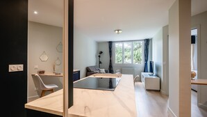 A modern kitchen with a central island, a dining area with a sofa, and a window with curtains. - Les Pommaries - Calm T2 near the Lake (Annecy)