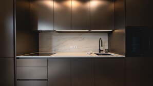 Una cocina moderna con encimera de mármol, armarios empotrados y campana extractora de acero inoxidable.