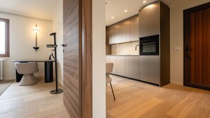 Una cocina moderna con electrodomésticos integrados, una zona de comedor con mesa y sillas, y piso de madera.