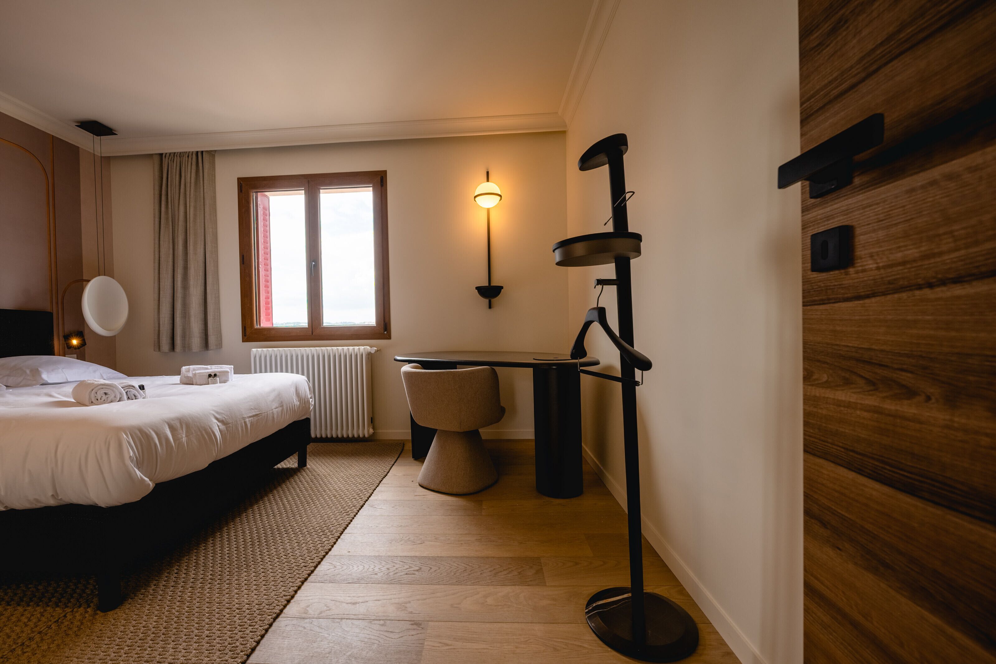 A bedroom with a bed, bedside table, lamp, and a window with curtains.
