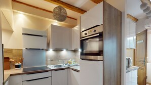 Een moderne keuken met witte kastjes, roestvrijstalen apparatuur en houten balken in het plafond.