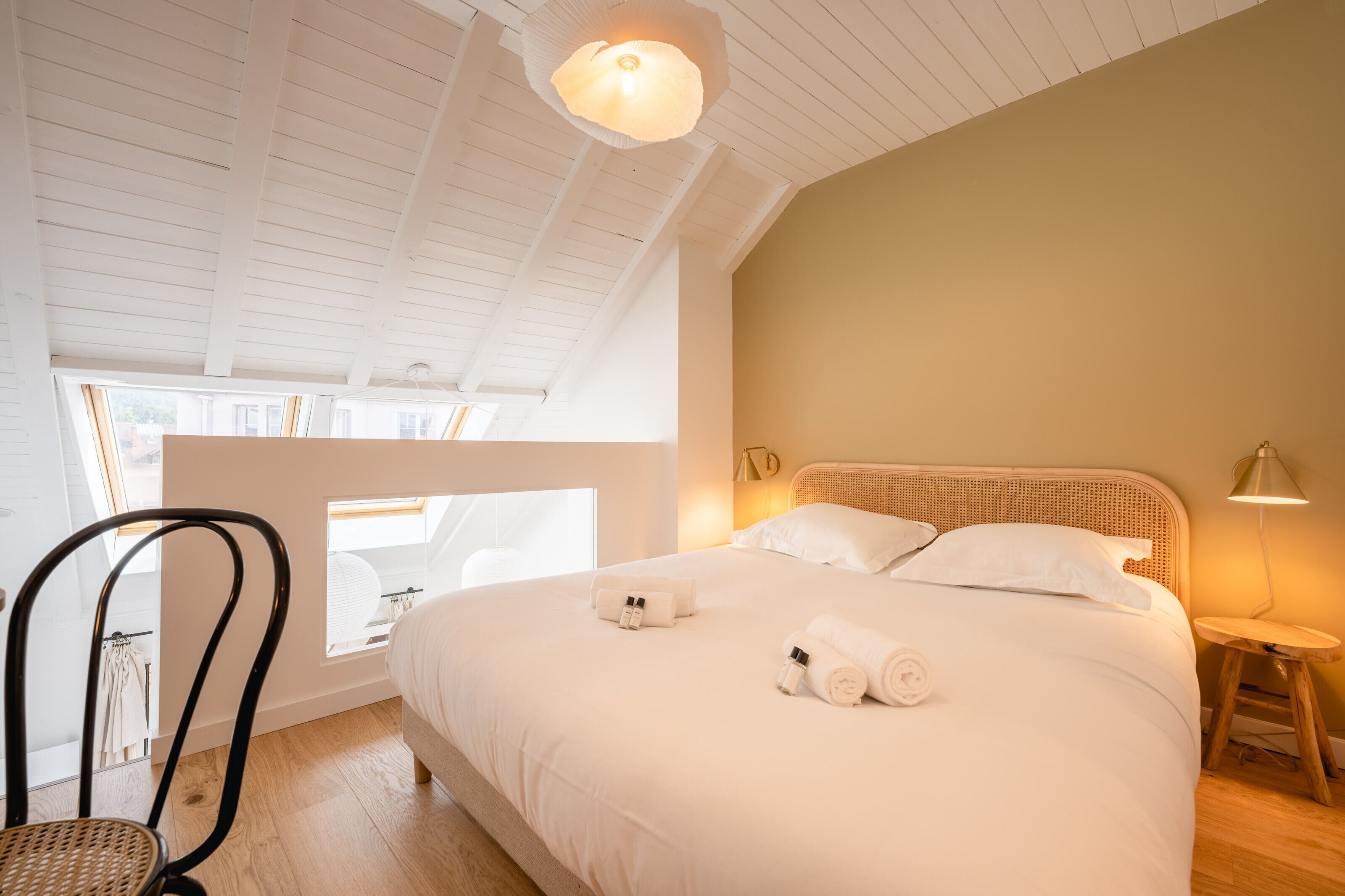 Una camera da letto con un letto grande, una sedia, un comodino e una lampada.