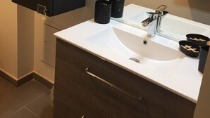 A modern bathroom with a white sink, dark cabinets, and a mirror above the sink. - Le Confort Annecy (terrasse & parking privé) (Annecy)