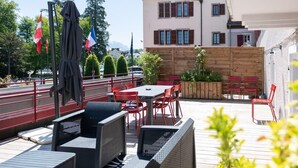 An outdoor patio with wicker furniture, red chairs, and a table. - OURAL, Annecy Rent Lodge (Annecy)