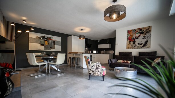 Un salon moderne comprenant un coin repas, une cuisine et une grande œuvre d’art accrochée au mur.