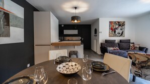 Une cuisine moderne avec un coin repas, comprenant une table ronde dressée pour quatre personnes, avec des assiettes, des verres et un vase contenant des objets décoratifs.