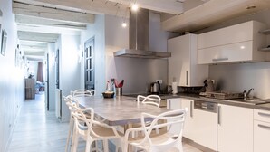Una cocina moderna con armarios blancos, una isla central con sillas y una cafetera a la vista.