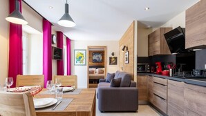 A modern kitchen with wooden cabinets, a dining area with a wooden table and chairs, and a grey sofa. - HIMALAYA, Annecy Rent Lodge (Annecy)