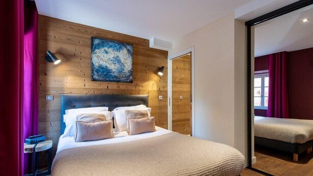 A modern bedroom with a wooden headboard, a large bed with white linens, a map artwork on the wall, and a mirror reflecting the room. - HIMALAYA, Annecy Rent Lodge (Annecy)