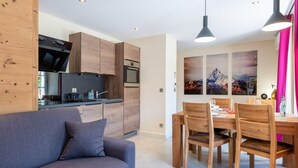 A modern kitchen with wooden cabinets, a built-in oven, and a dining area with wooden chairs and a table. - HIMALAYA, Annecy Rent Lodge (Annecy)