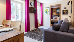 A modern living room with a sofa, a dining table with chairs, and a TV mounted on the wall. - HIMALAYA, Annecy Rent Lodge (Annecy)
