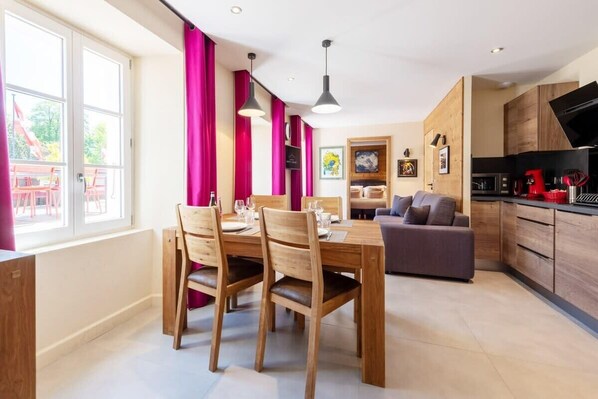 A modern kitchen with wooden cabinets, a dining area with a wooden table and chairs, and a sofa. - HIMALAYA, Annecy Rent Lodge (Annecy)