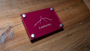 A red square object with the text "CARPATES" and a mountain line design on a wooden surface.