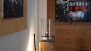 A modern living room with a wooden wall panel, a painting of a lighthouse, and a glass table with a candle holder. - APPENNINS, Annecy Rent Lodge (Annecy)