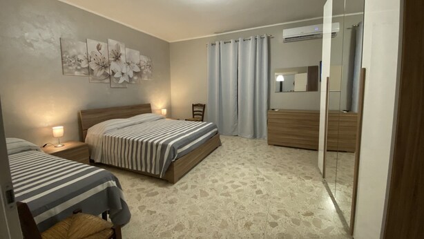 A bedroom with two beds, a nightstand, a chair, a mirror, and a ceiling light.