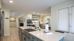 A modern kitchen with a central island, built-in appliances, and a dining area with a table and chairs. - 23 Willow Oak West: Sea Pines Home, 4BR, Pool, Hot Tub, Free Bikes (Hilton Head Island)