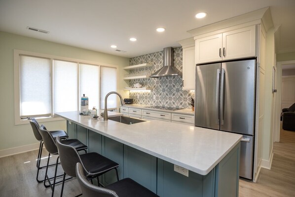 A modern kitchen with a central island, stainless steel appliances, and a backsplash with a geometric pattern.
