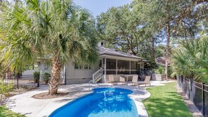 A backyard with a swimming pool, a covered patio, and a house. - 23 Willow Oak West: Sea Pines Home, 4BR, Pool, Hot Tub, Free Bikes (Hilton Head Island)