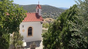 Ein kleines Gebäude mit rotem Ziegeldach, einem Glockenturm und einem Kreuz an der Fassade.
