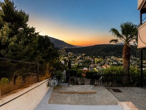 Un patio empedrado con escalones que conducen a un balcón con vistas a un pueblo al atardecer.