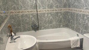 Un baño con bañera, lavamanos e inodoro.
