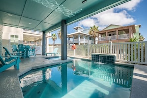 Une piscine dotée d’une zone couverte, d’un espace extérieur aménagé et offrant une vue sur un immeuble à plusieurs étages avec des balcons.