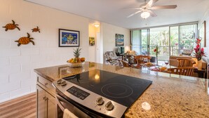 A modern kitchen with a central island, a dining area with a view, and a ceiling fan.
