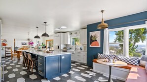 A modern kitchen with a central island, white cabinets, and a checkered floor pattern.