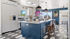 A modern kitchen with a central island, white cabinets, and a blue accent wall.