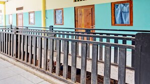 A row of rooms with teal walls, wooden doors, and a metal railing. - OYO Life 93037 Nova Jaya Homestay Syariah  (Jogoroto)