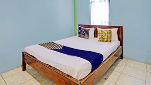 A single bed with a wooden frame, white and blue bedding, and patterned pillows. - OYO Life 93037 Nova Jaya Homestay Syariah  (Jogoroto)