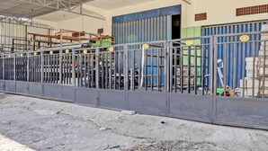 A metal fence with a gate, a covered area with a roof, and a building with a blue door and windows. - OYO Life 93037 Nova Jaya Homestay Syariah  (Jogoroto)