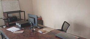 Un escritorio de madera con una computadora portátil, papeles, un vaso y un teclado.